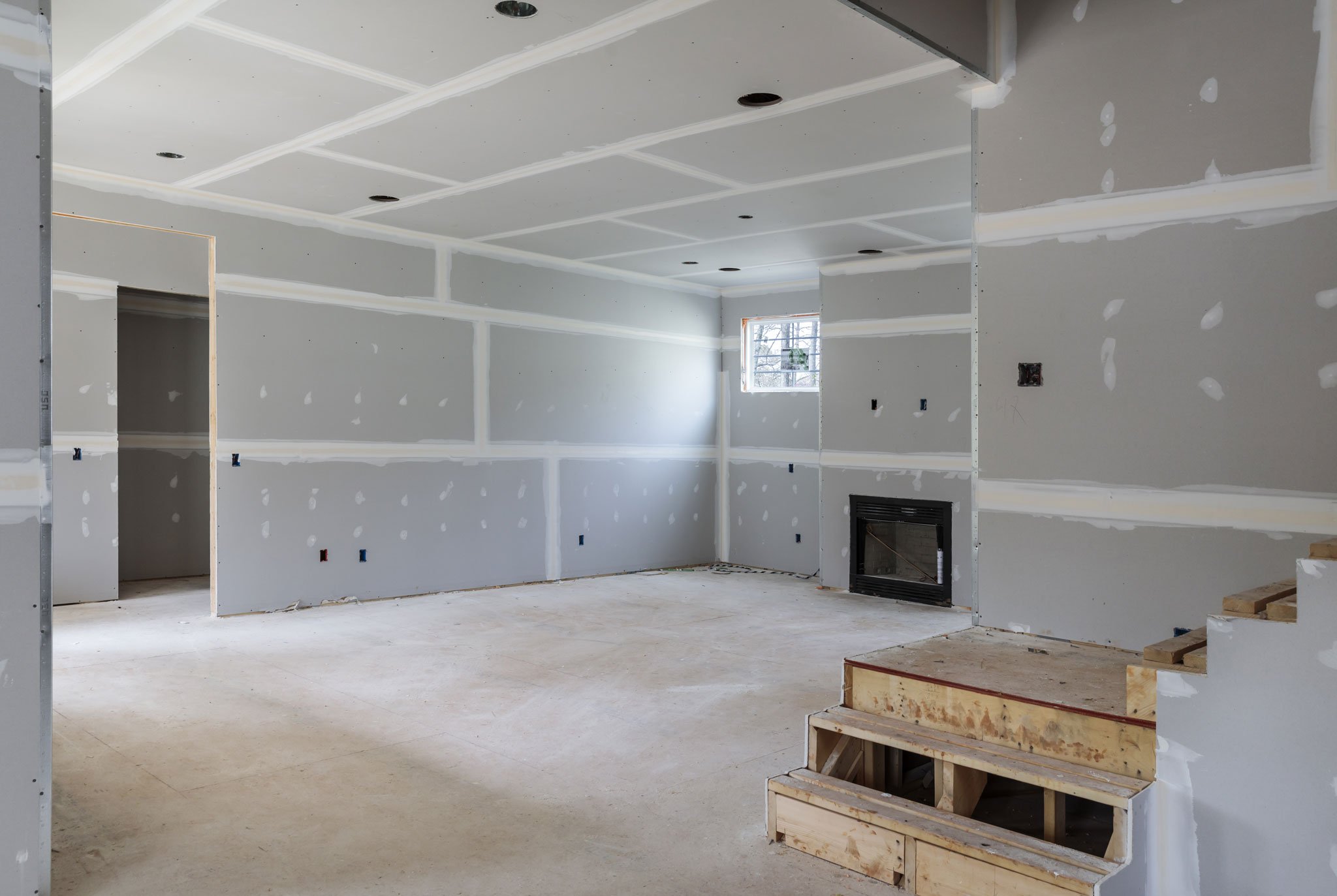 Interior of a room under construction with unfinished drywall and a fireplace insert.